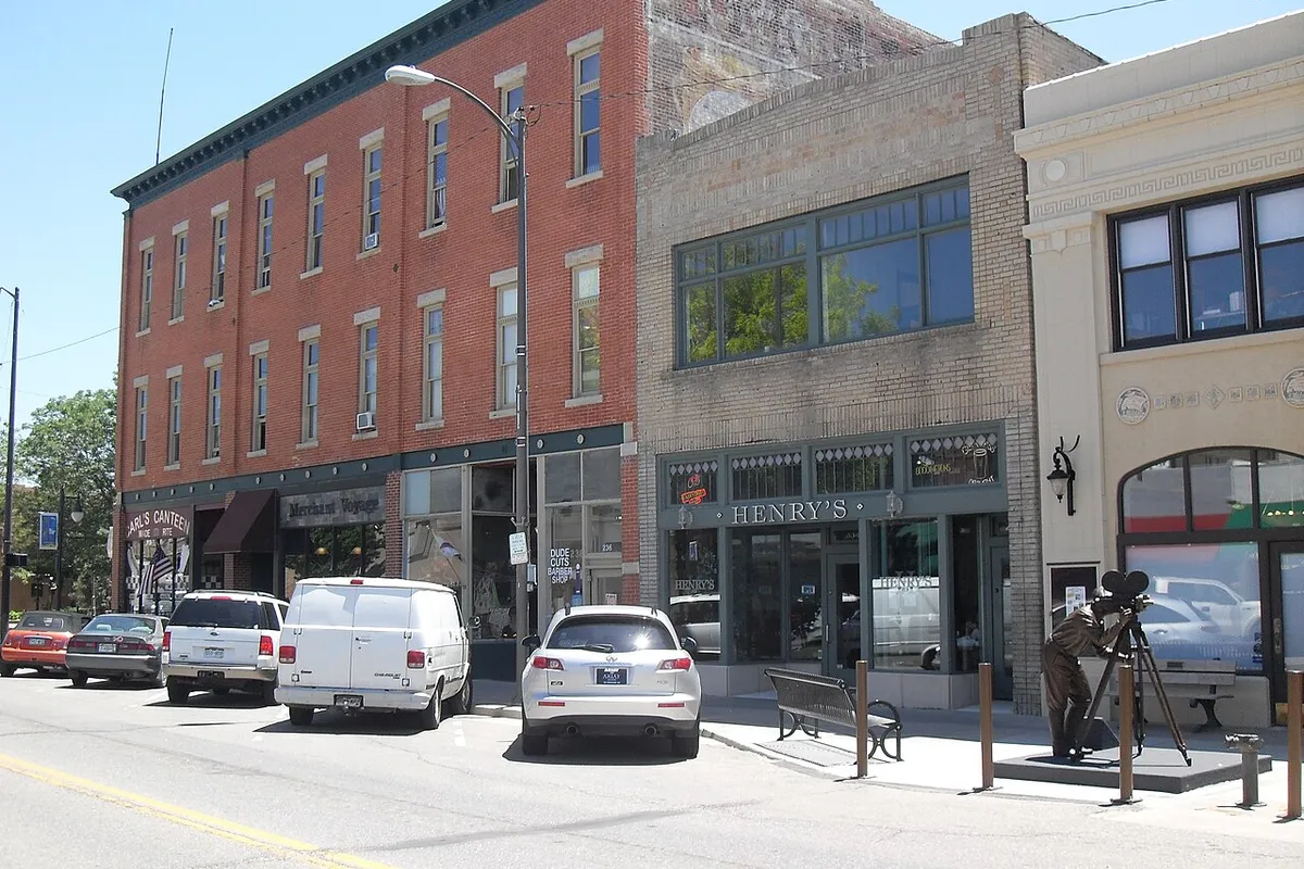 Henry's Pub's green-framed storefront with HENRY'S lettered above the windows, in a tan-brick two-story building on 4th Street between a red-brick block and the Rialto Theater, on a sunny summer day.